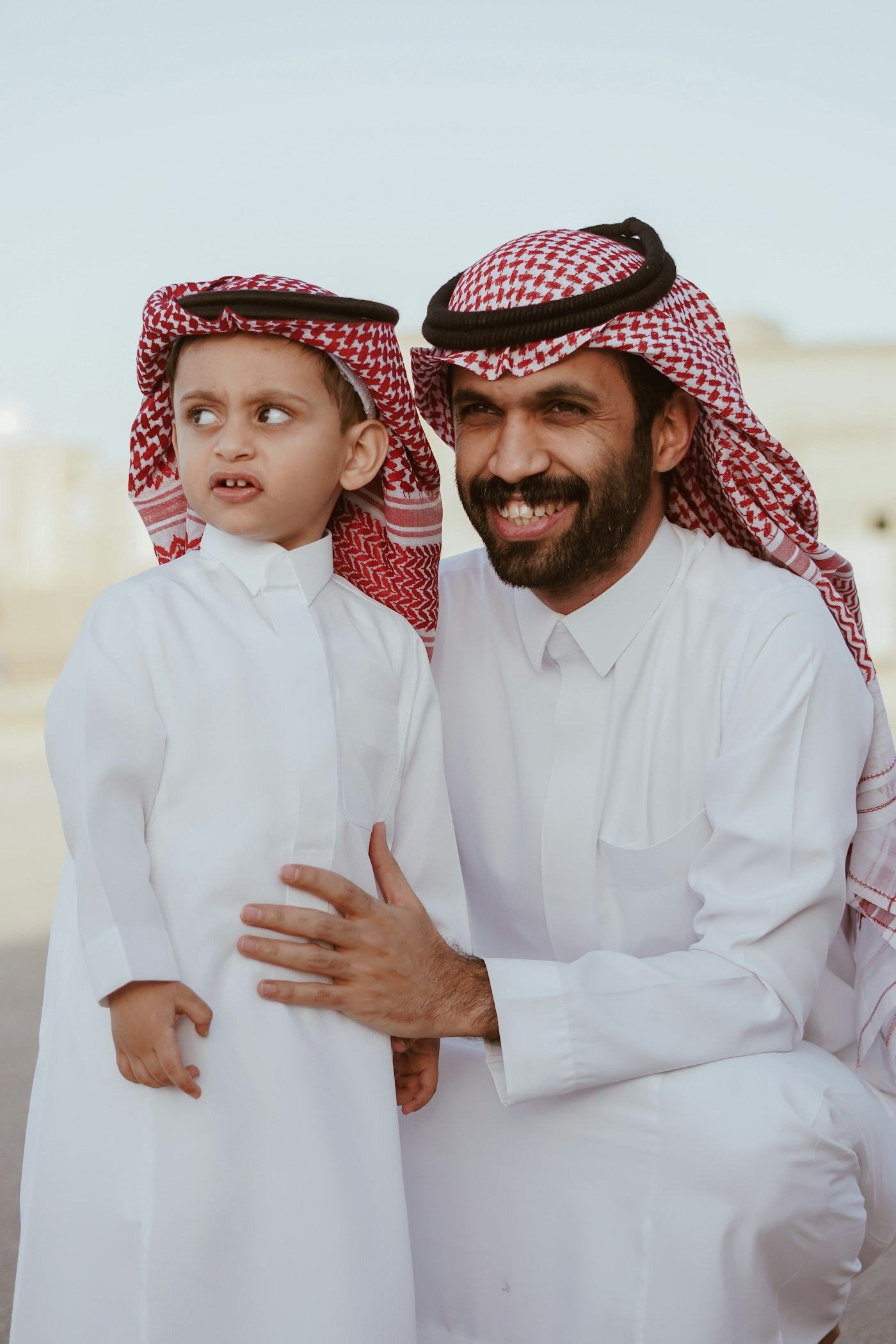 A father and his young son in traditional Gulf dress