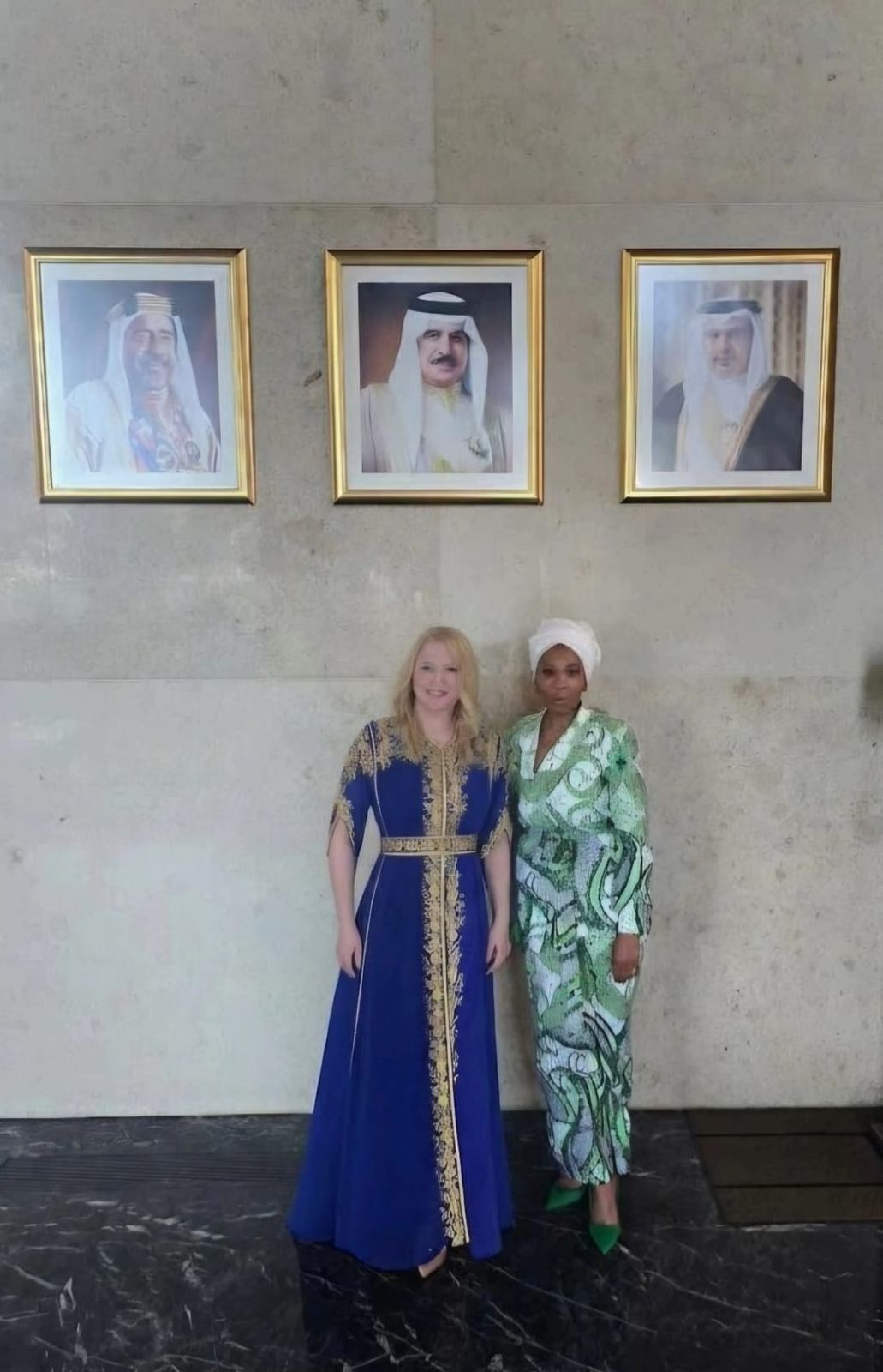Two guests in formal dress beneath official portraits