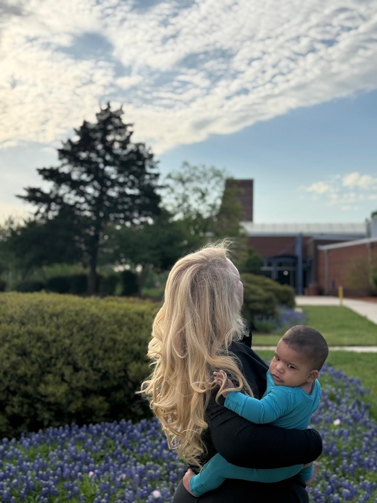 A Guild member holding a baby in a garden