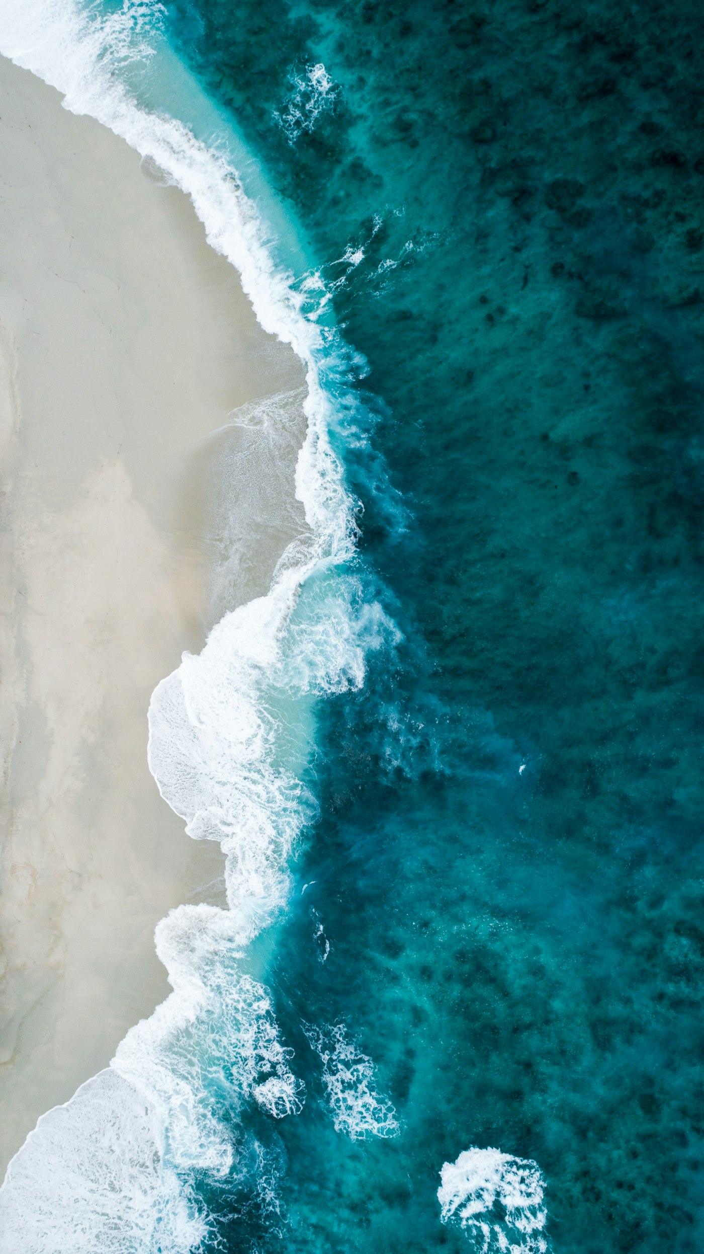Aerial view of surf meeting a white-sand beach